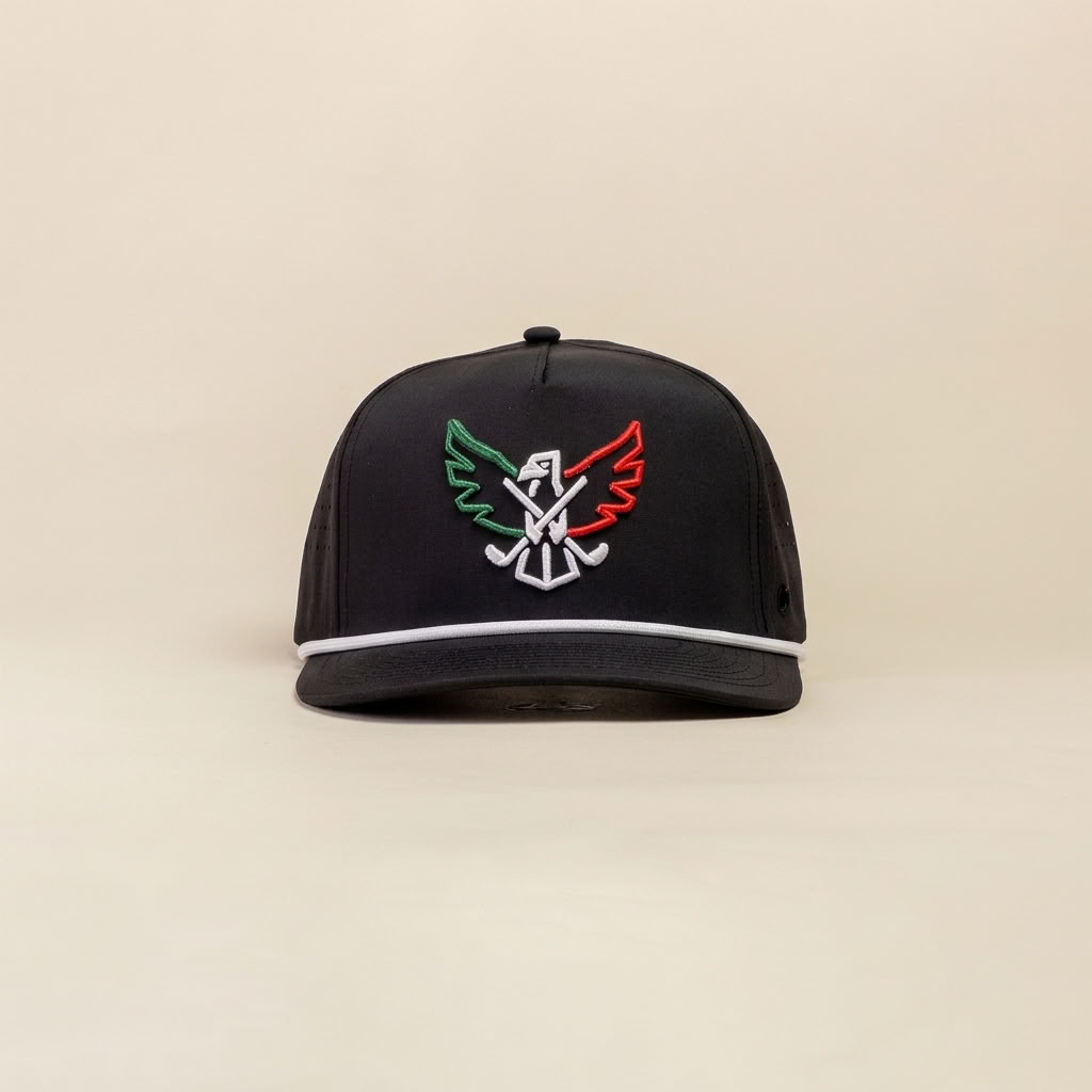A black snapback cap with a structured front panel featuring an embroidered eagle logo in green, white, red, and black, with a white piping accent along the edge of the brim, set against a solid beige background.